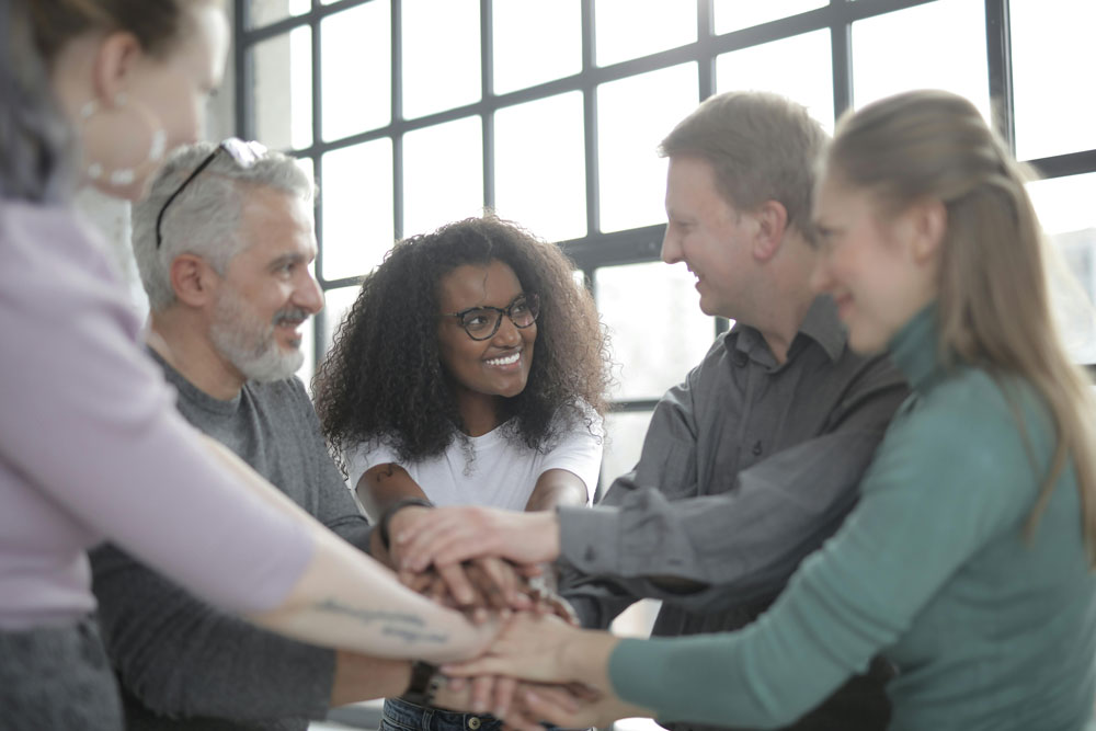 Group of people placing hands on top of each other in the center as if about to cheer