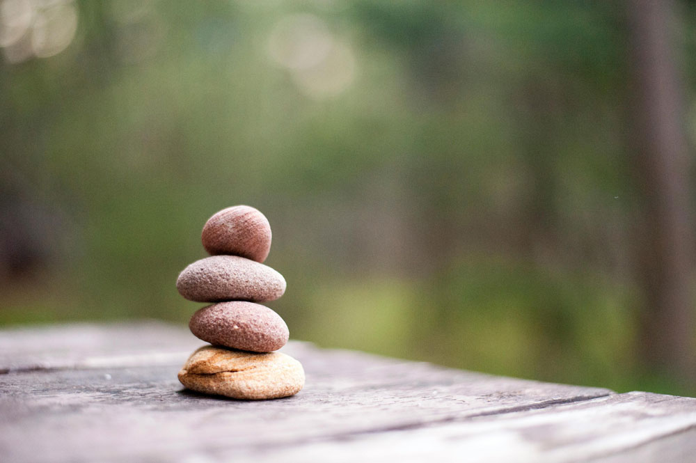 Four rocks stacked on top of one another in a forest