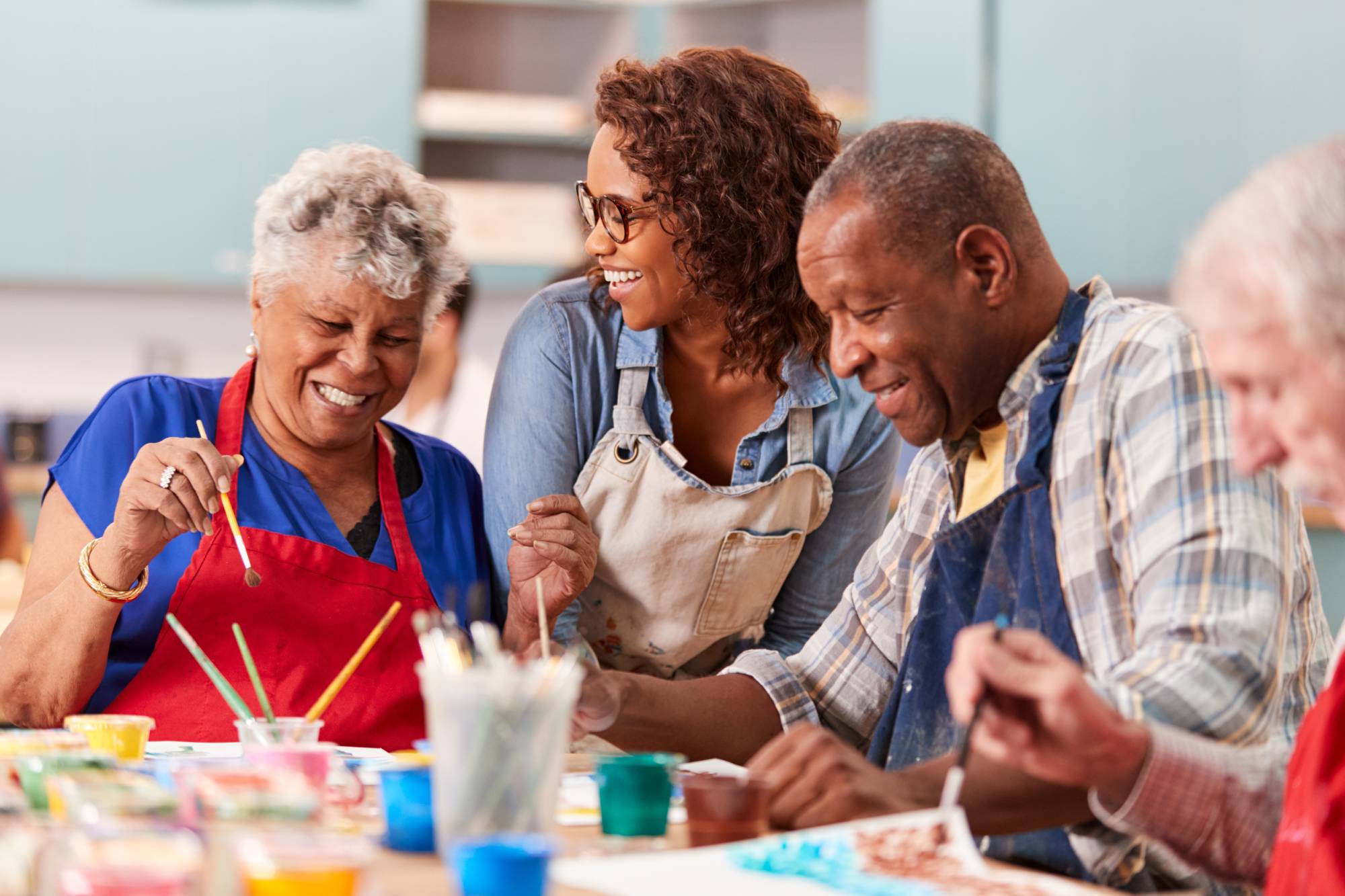 Seniors smiling and participating in an art activity with a staff member